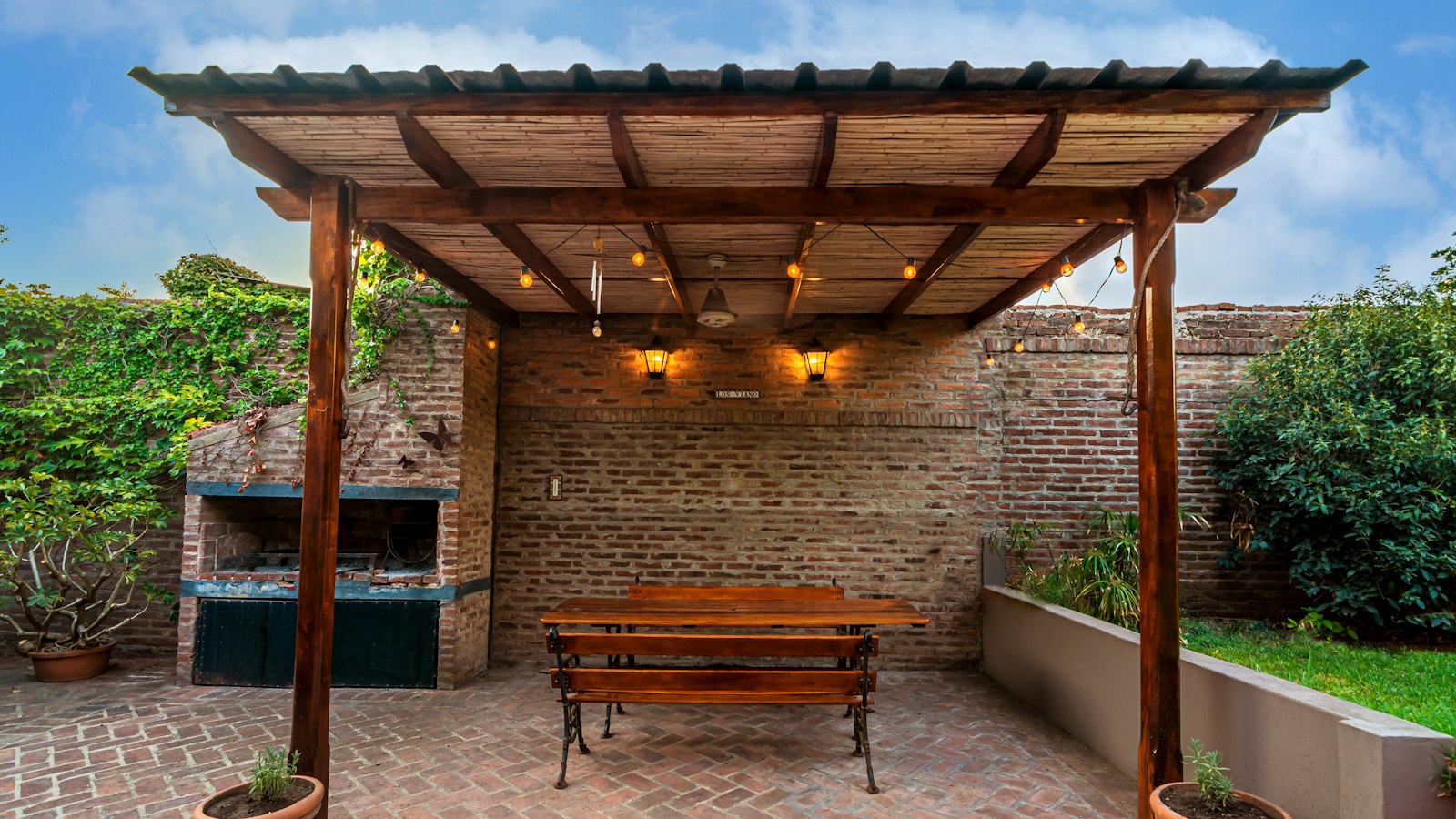 A brick patio with a pergola, picnic bench and outdoor grill area (photo: Rafael Hoyos Weht / Unsplash)