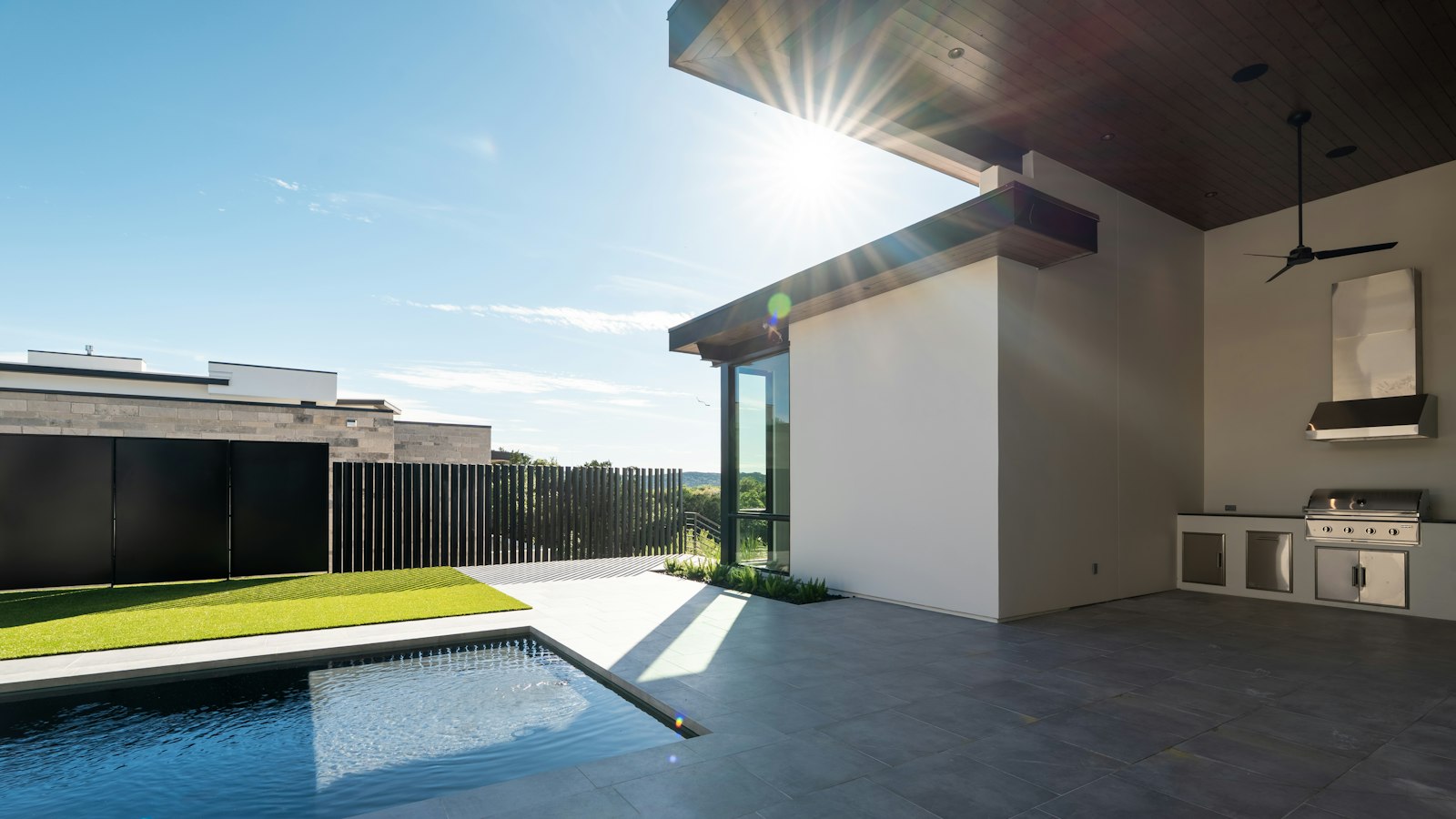 A modern covered patio with an outdoor kitchen next to a pool (photo: Salvo Media LLC / Unsplash)