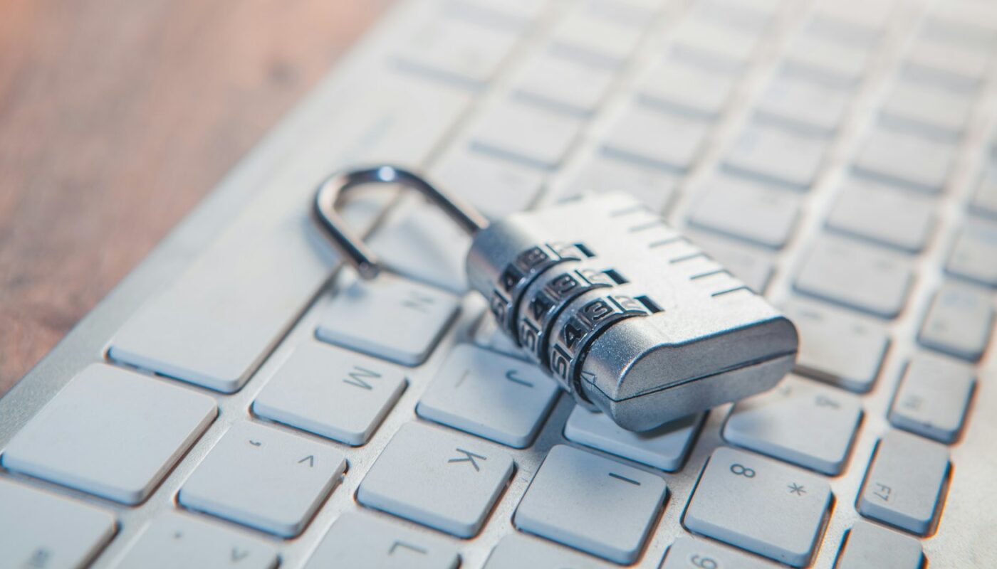 A combination padlock resting on a white laptop keyboard (photo: Sasun Bughdaryan / Unsplash)