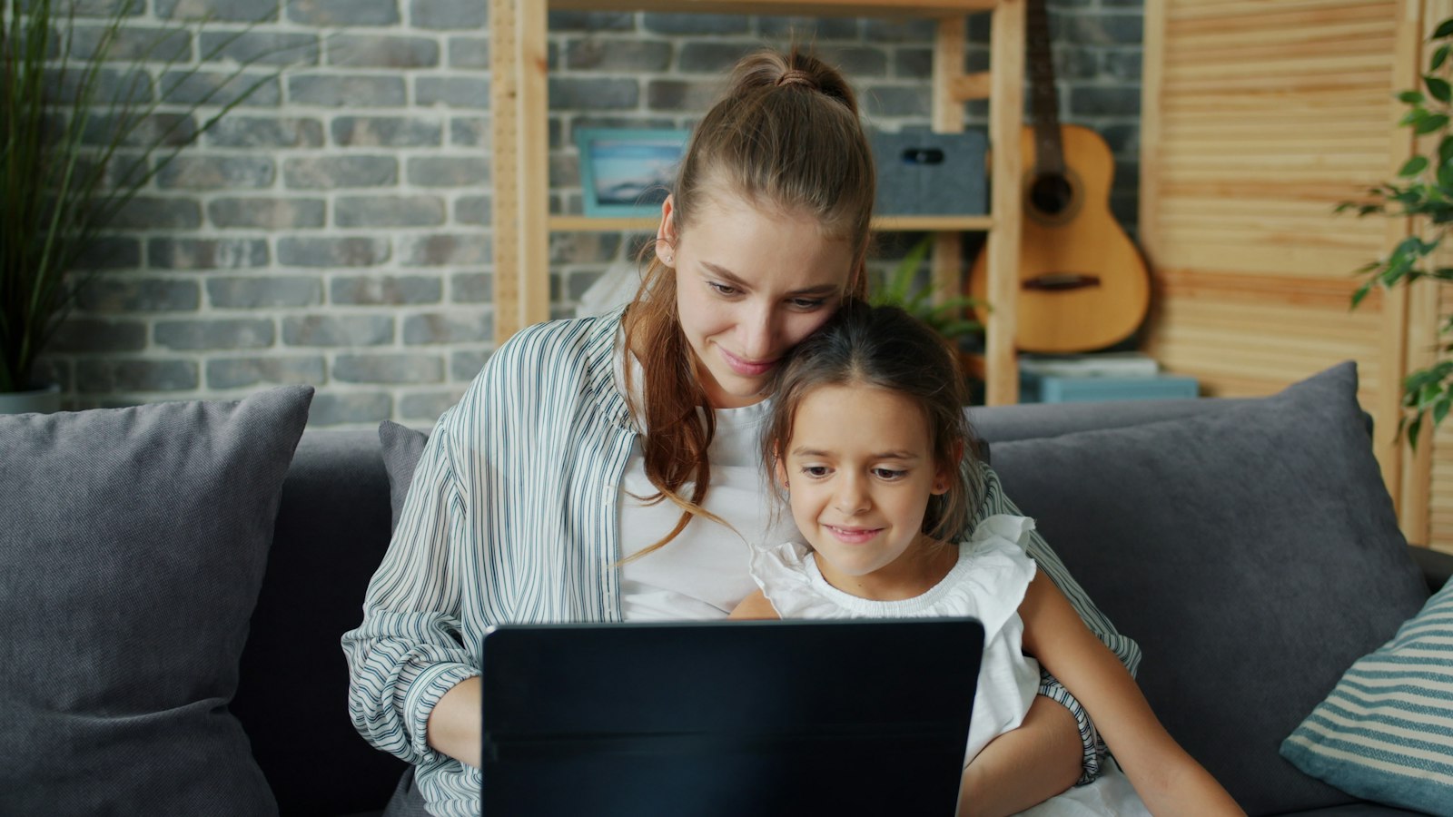 A mother and daughter using a laptop together on a sofa (photo: Vitaly Gariev / Unsplash)