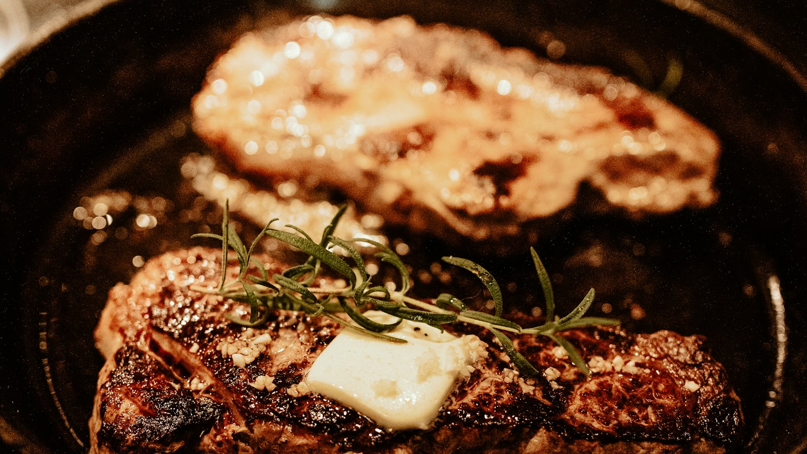 A seared steak topped with butter and rosemary in a pan (photo: Sandra Seitamaa / Unsplash)