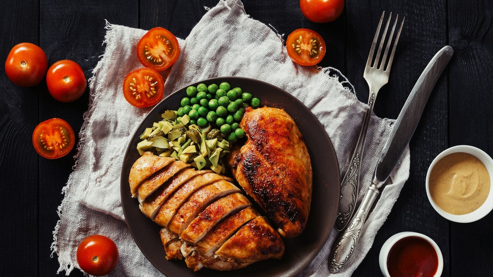Grilled chicken breasts with peas and cherry tomatoes on a plate (photo: Elena Leya / Unsplash)