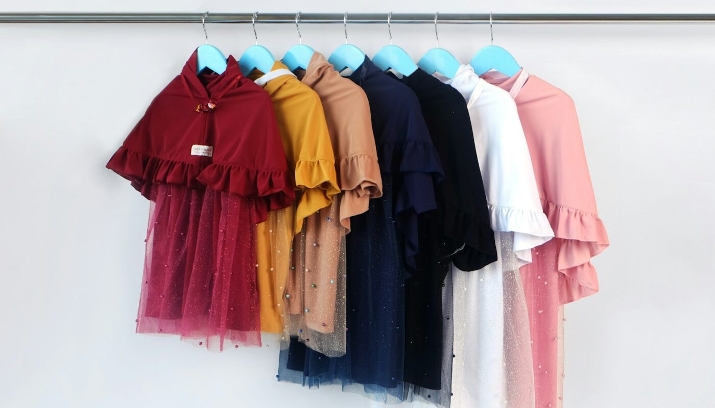A rail of children’s dresses hanging in graded colours (photo: Hafizha Anisa / Unsplash)