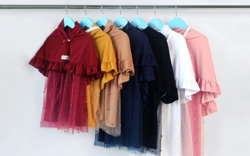 A rail of children’s dresses hanging in graded colours (photo: Hafizha Anisa / Unsplash)