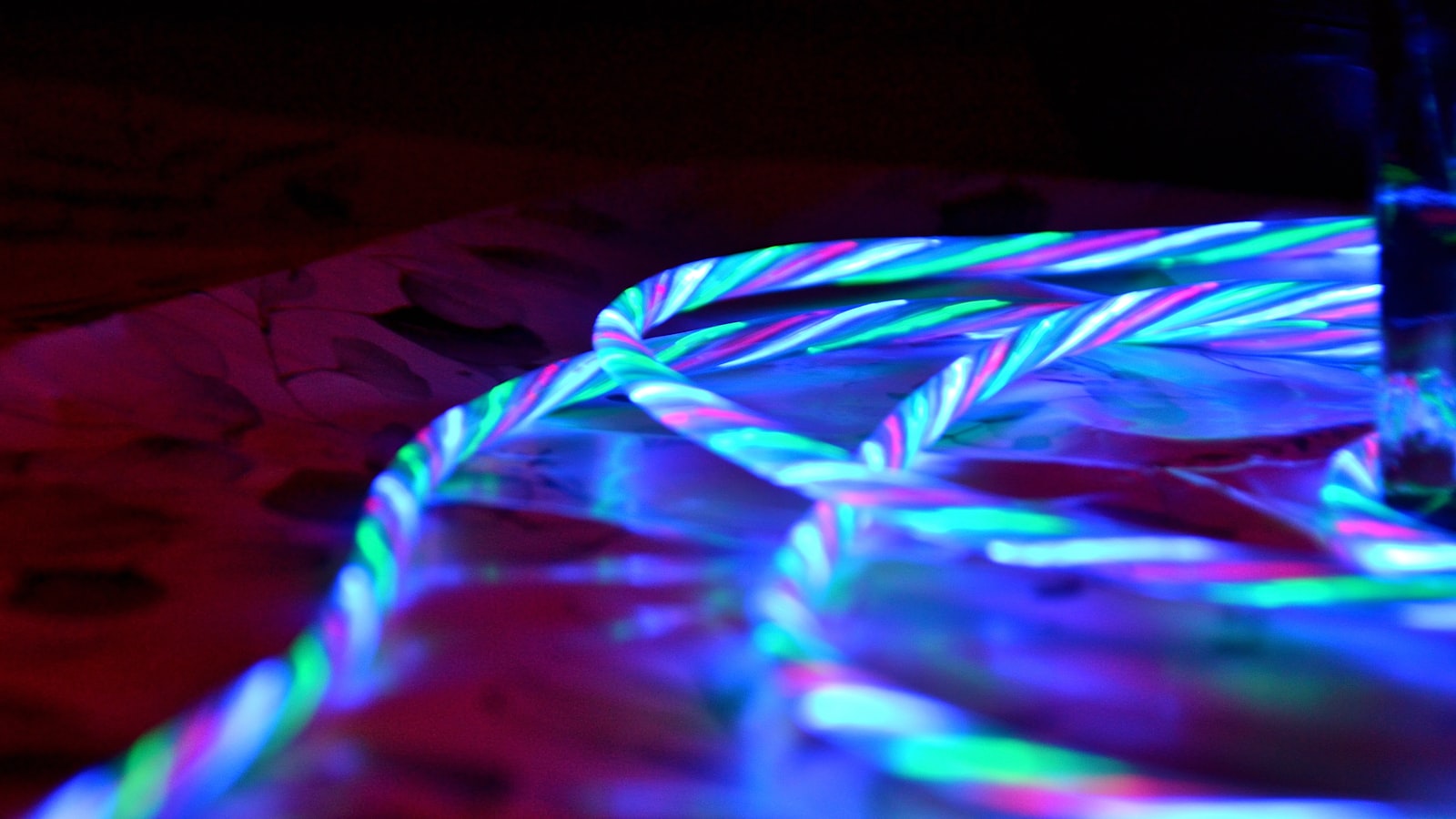 Twisted colourful light strands on a dark surface (photo: Kristiina Klaas / Unsplash)