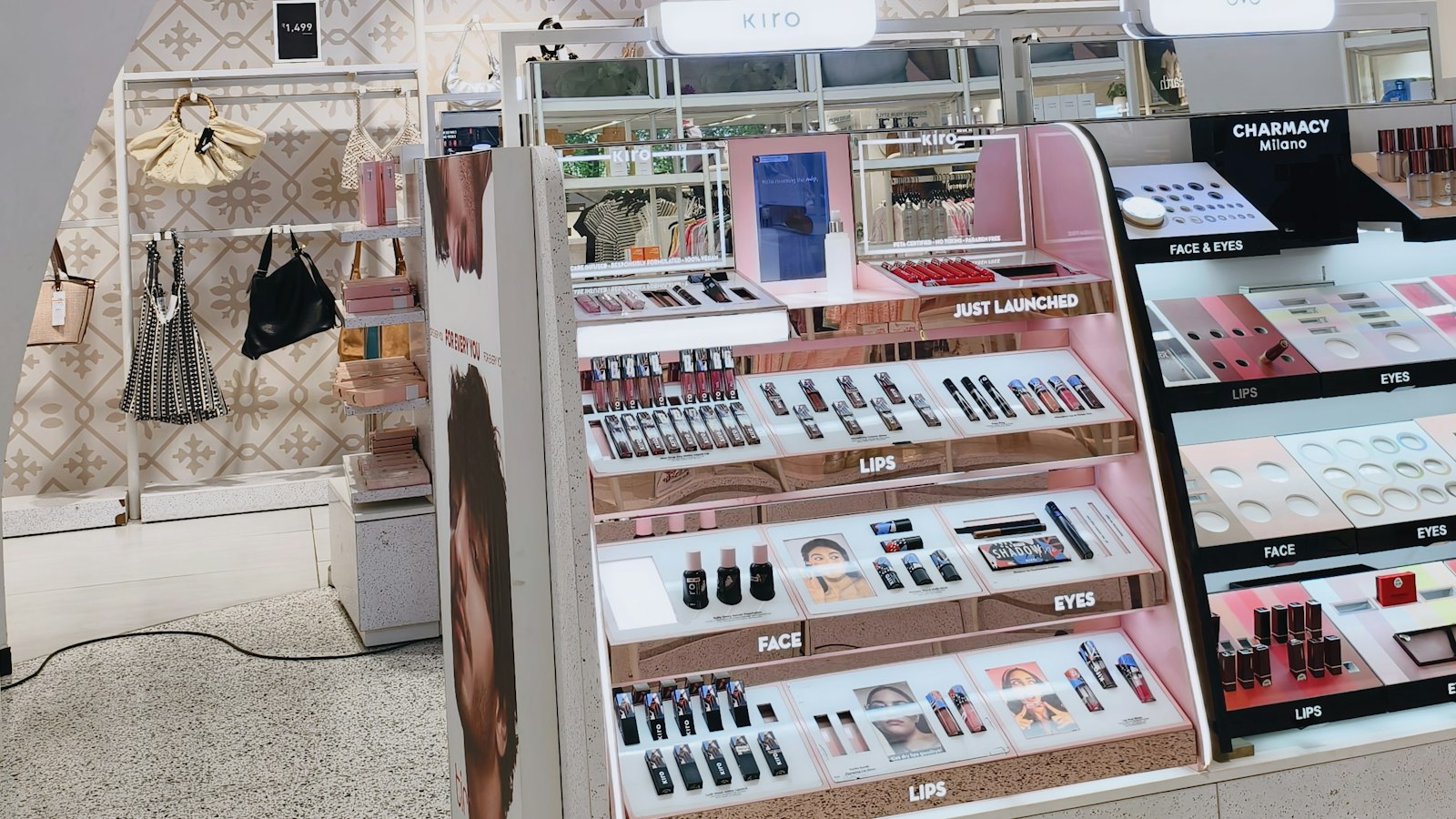 Open shelves of lipsticks and eye products arranged by shade in a bright beauty shop