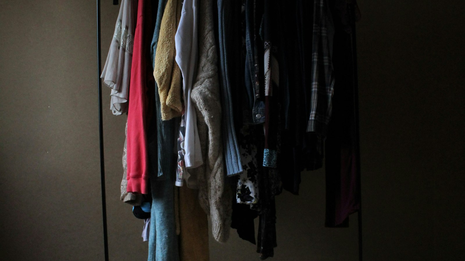 A densely packed clothing rail in a dim room (photo: Anne Nygard / Unsplash)
