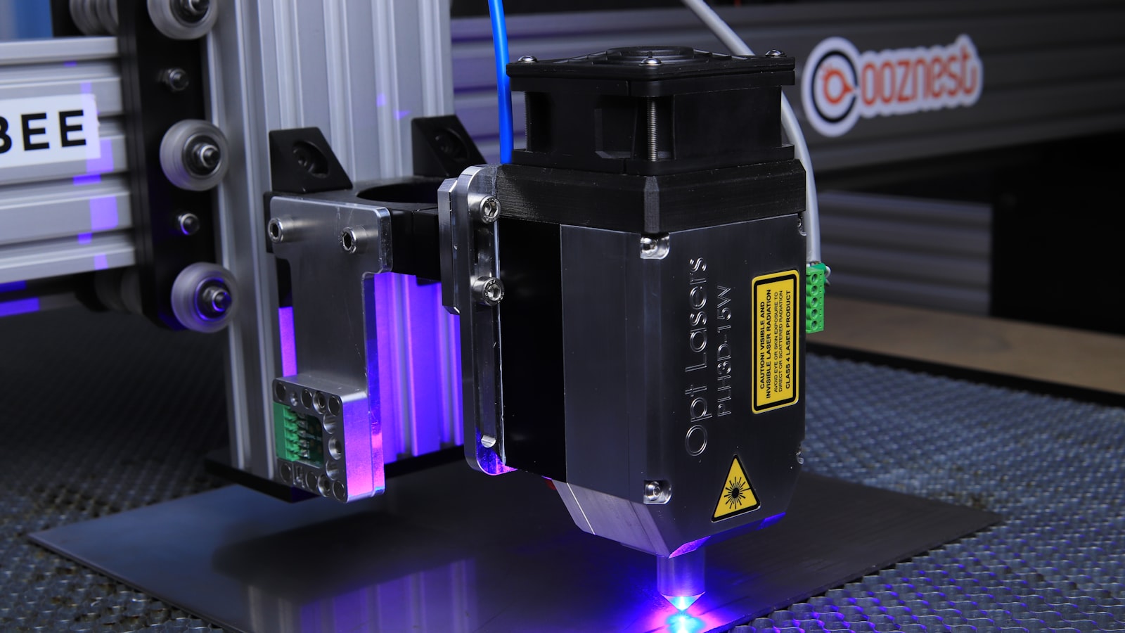 A desktop diode laser engraving a dark sheet on a honeycomb bed (photo: Opt Lasers / Unsplash)