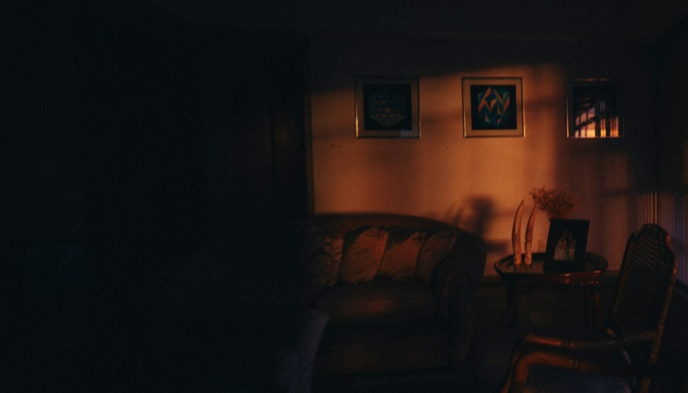 Dimly lit living room at night with framed art on the wall (photo: Helena Lopes / Unsplash)