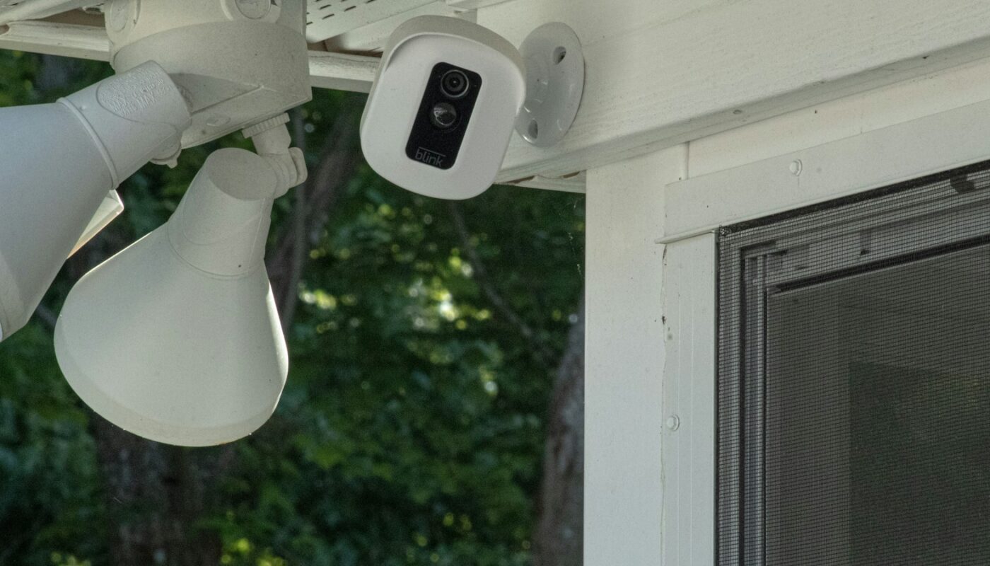 Security camera and floodlight mounted on a house porch (photo: Mary Oakey / Unsplash)