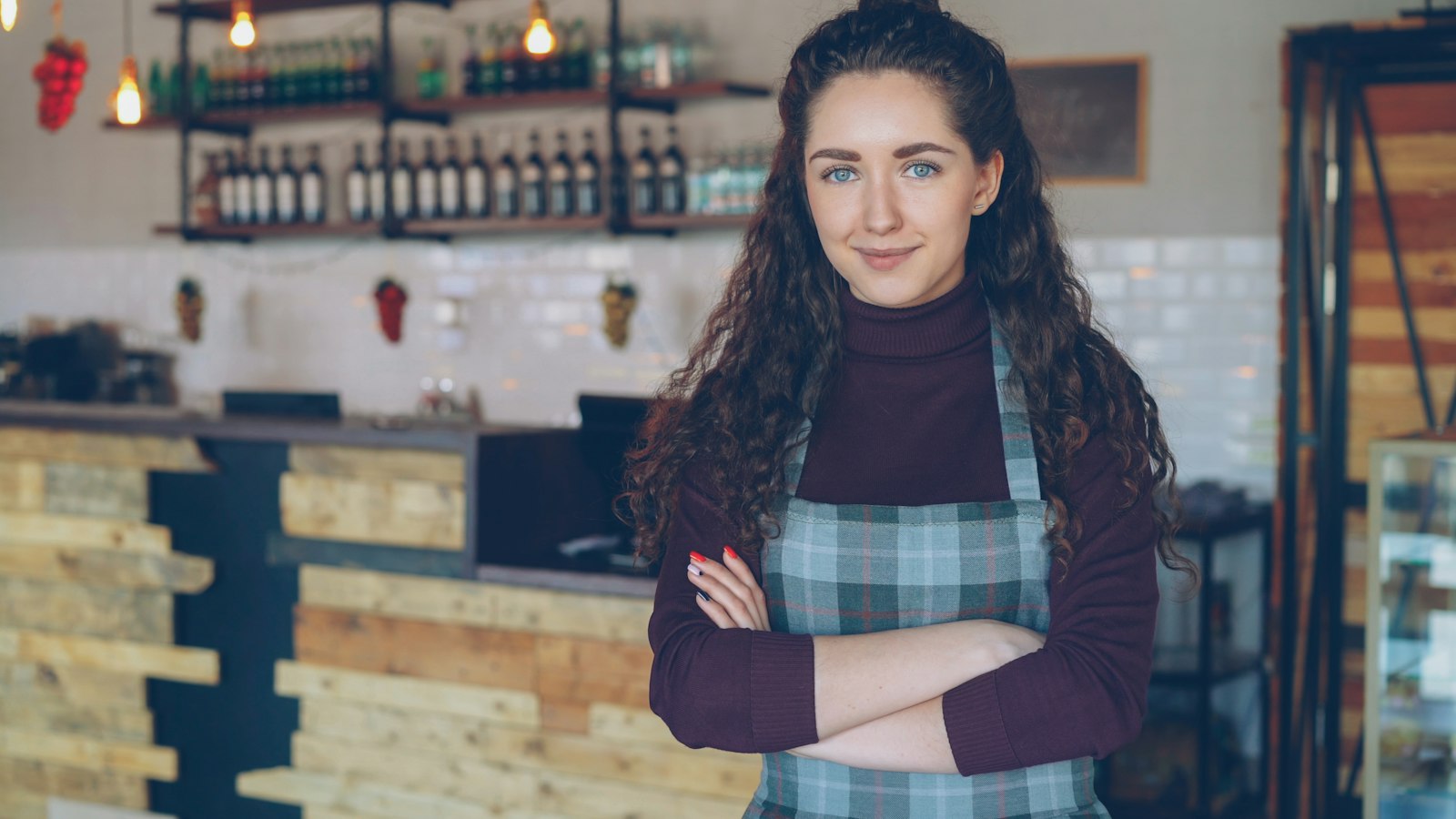 A cafe owner in an apron with arms folded (photo: Vitaly Gariev / Unsplash)