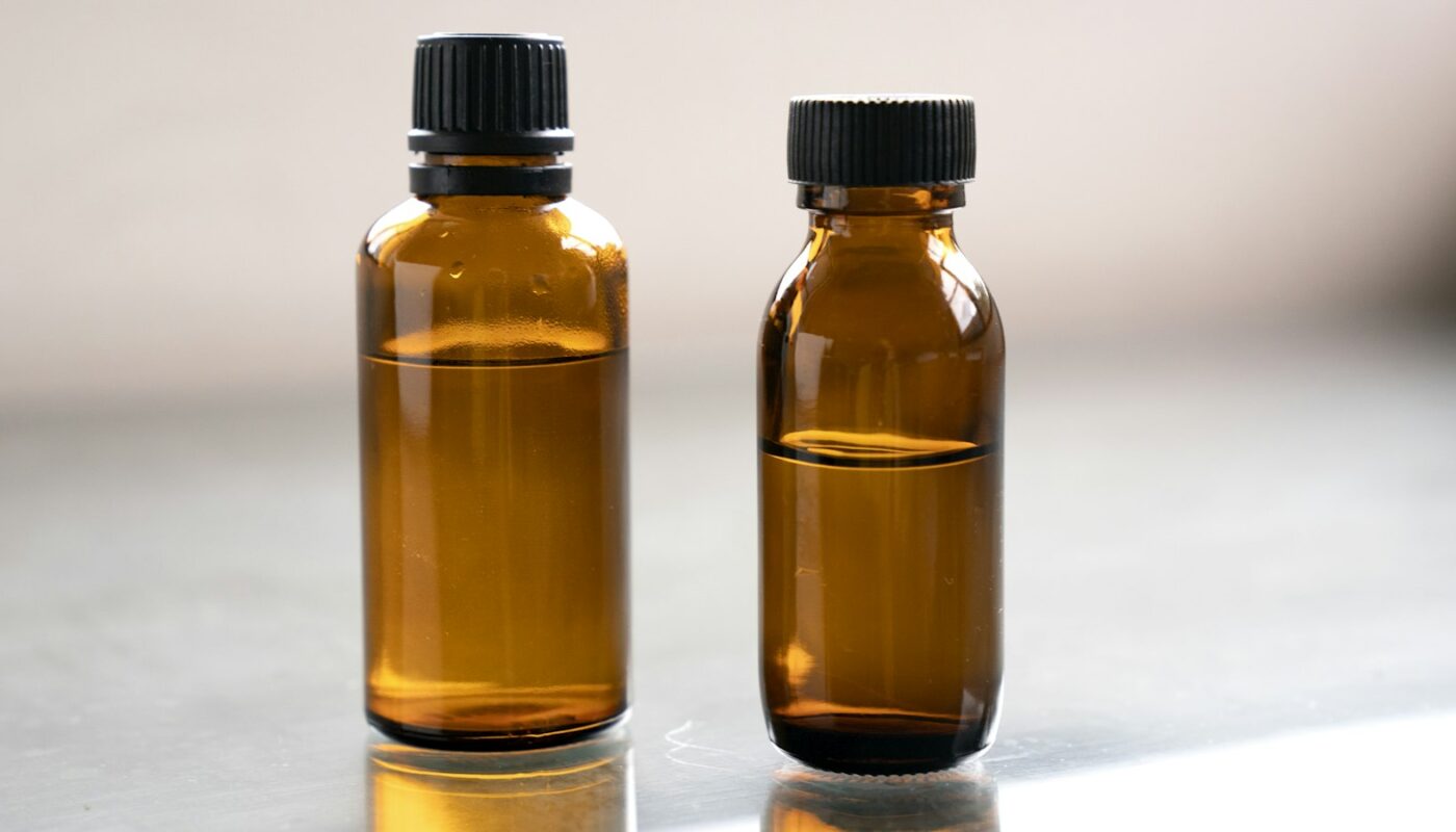 Two small amber glass bottles on a grey surface (photo: Denise Chan / Unsplash)