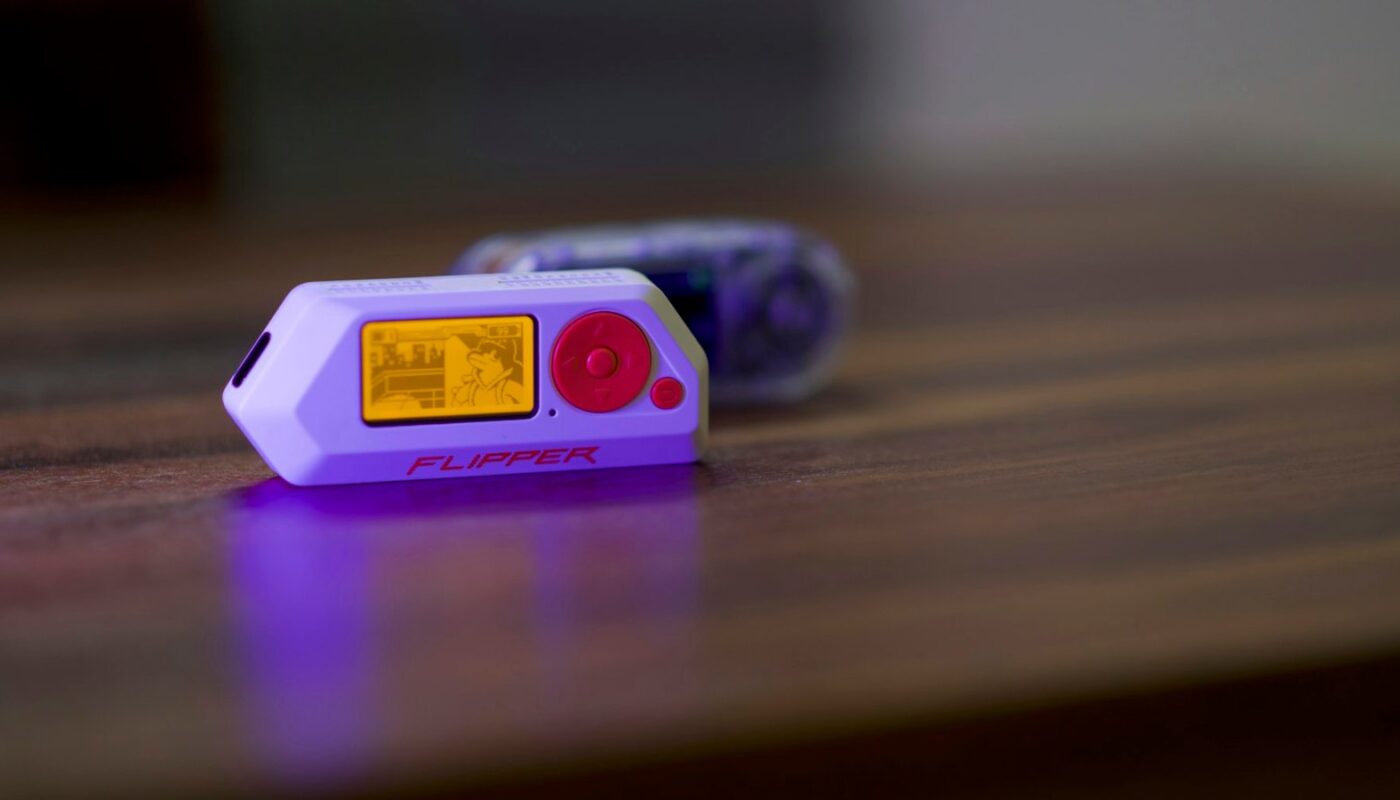 A Flipper Zero multi-tool device resting on a wooden desk with its screen lit