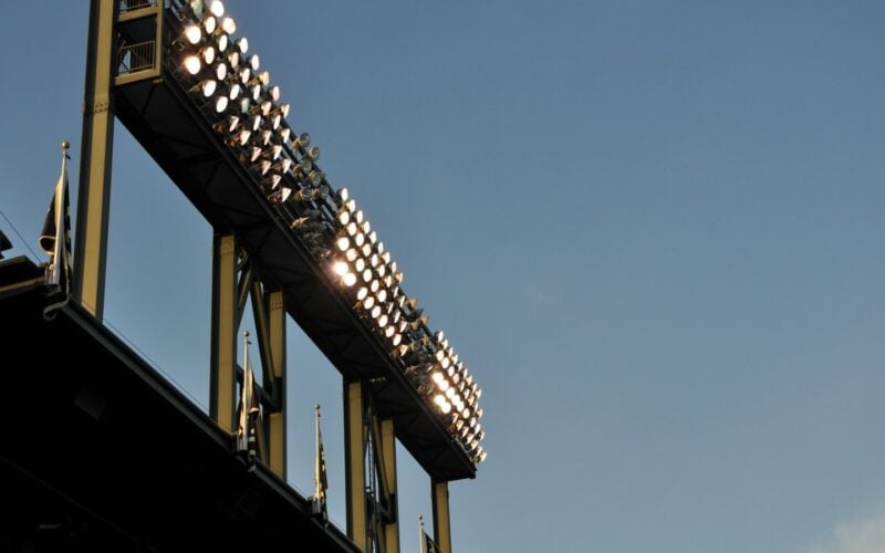 Stadium floodlight gantry lit against a dusk sky (photo: Marta Serrano / Unsplash)