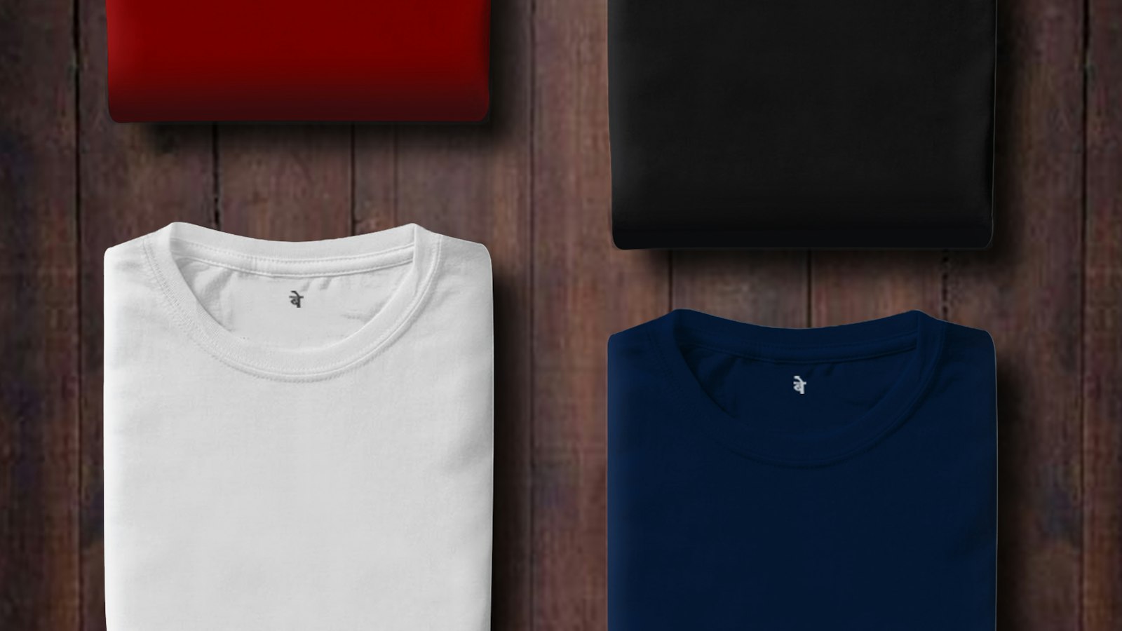 Three plain folded t-shirts in white, navy and black on a dark wooden surface (photo: Md Salman / Unsplash)