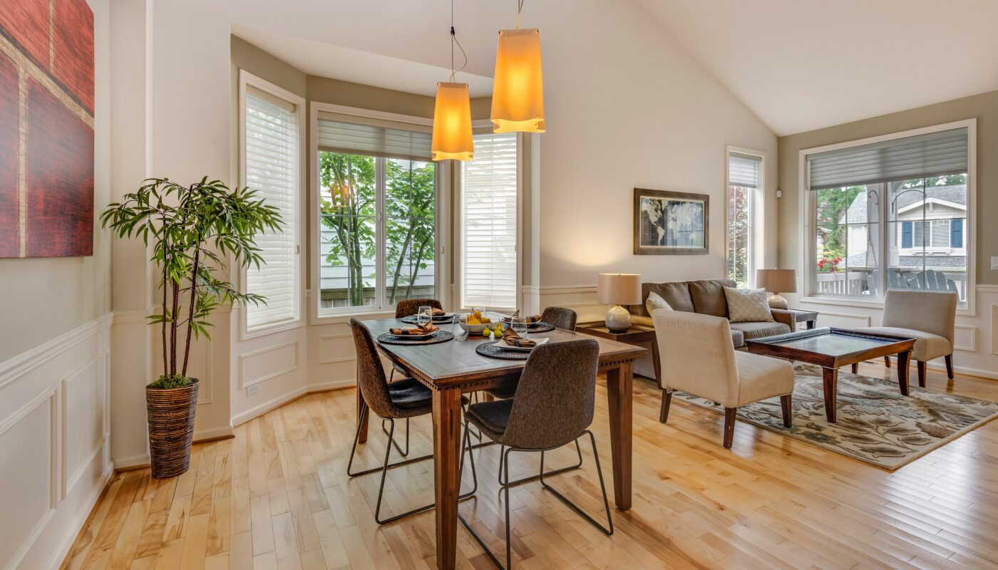Bright dining room with a wooden table, houseplant and large windows