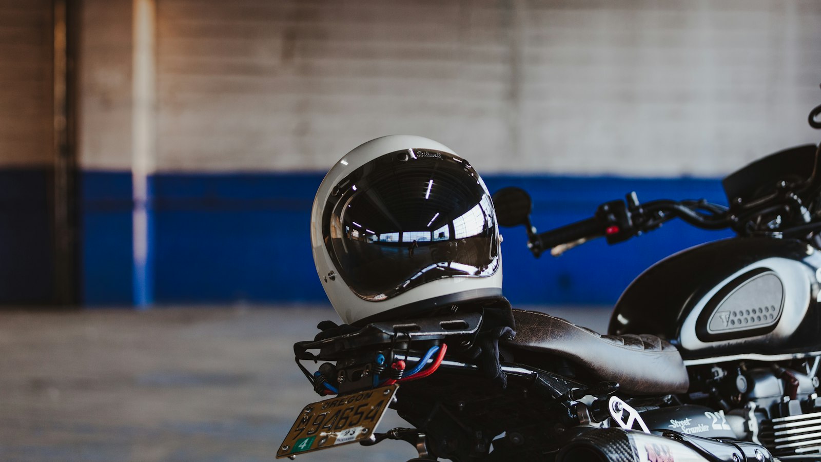 A full-face motorcycle helmet resting on the tail of a parked motorcycle (photo: Sean Benesh / Unsplash)
