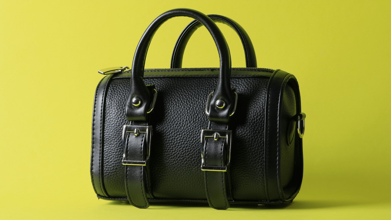 A black leather handbag against a lime background (photo: Mobina Ghazazani / Unsplash)