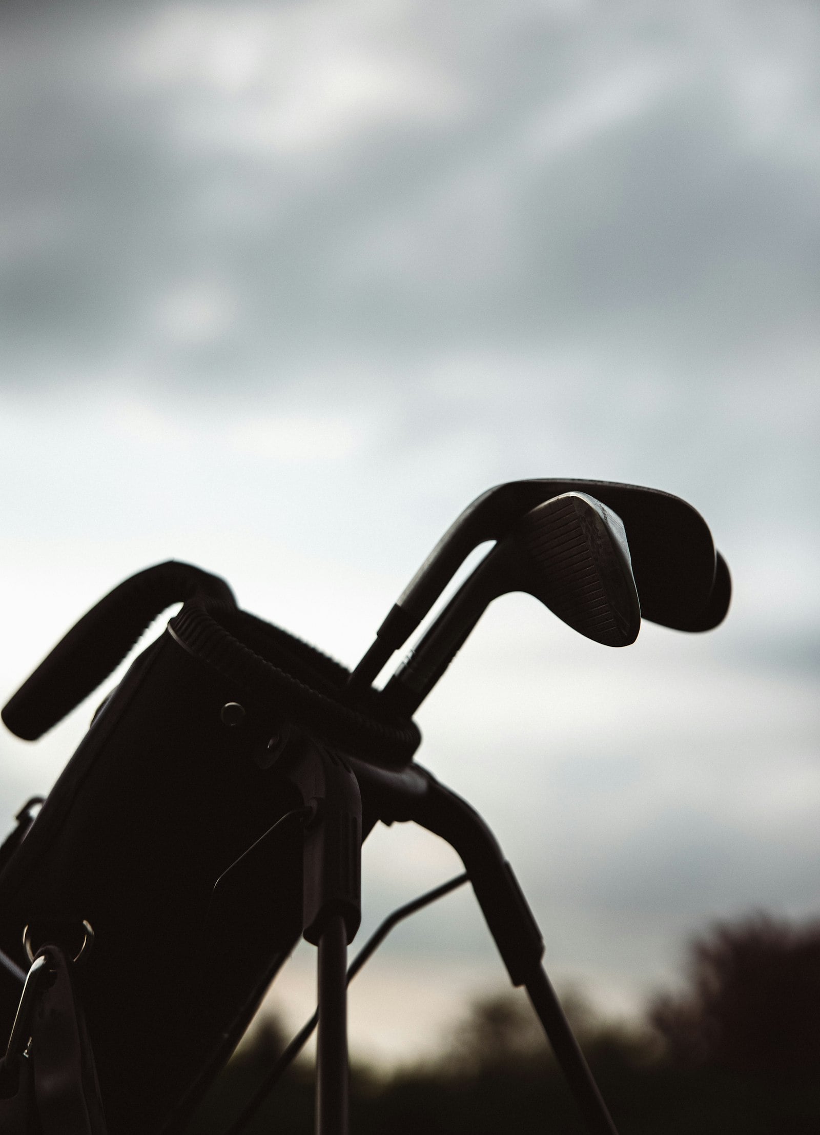 Golf clubs in a bag silhouetted against the sky (photo: Adrian Hernandez / Unsplash)