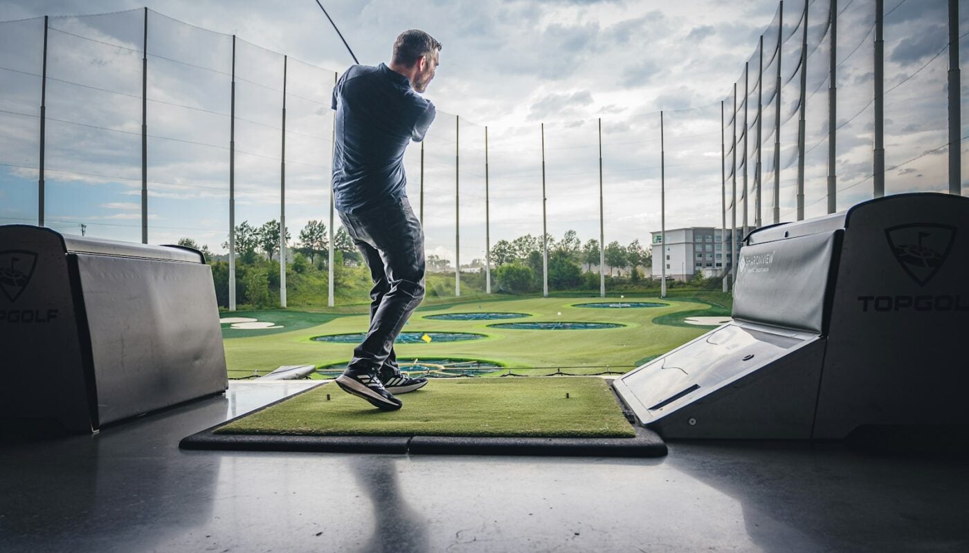 Golfer finishing a tee shot on a sunny course (photo: Matt Benson / Unsplash)
