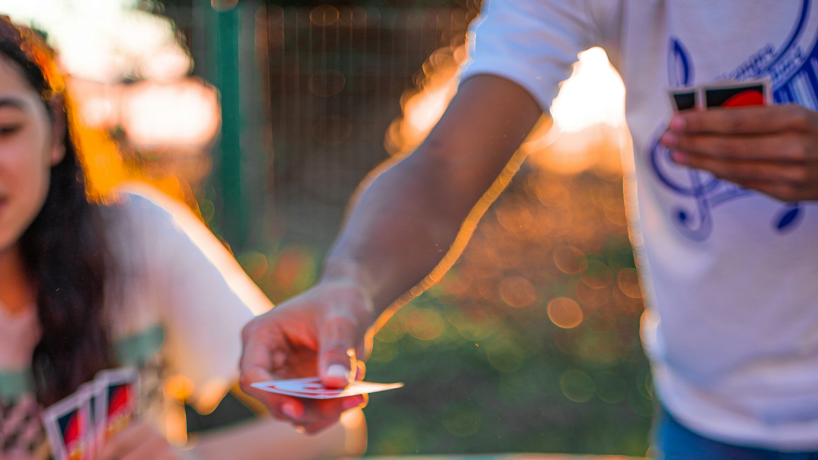 A group dealing and playing a card game on a blue table outdoors (photo: Ezequiel Garrido / Unsplash)
