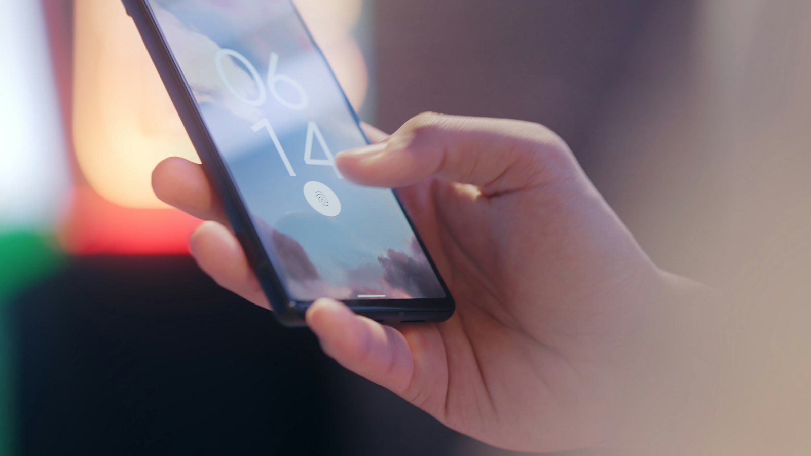 A close view of a hand holding a phone with the lock screen showing the time (photo: I'M ZION / Unsplash)