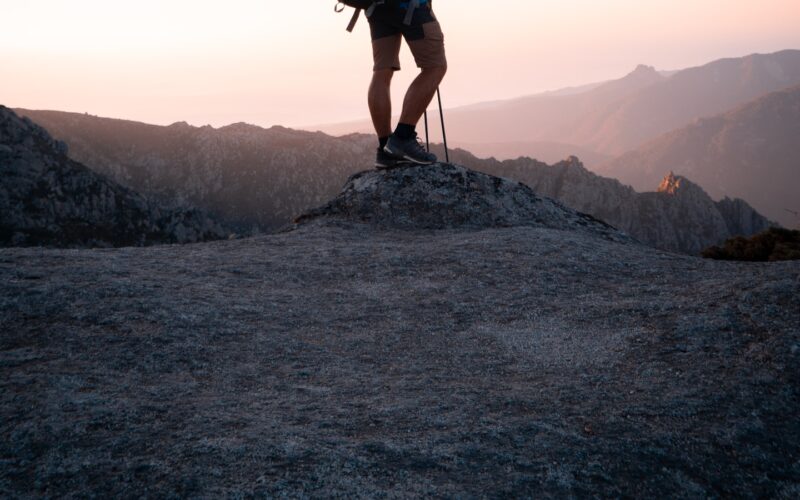 A hiker carrying a large backpack standing on a rocky ridge at dusk (photo: lucas Favre / Unsplash)