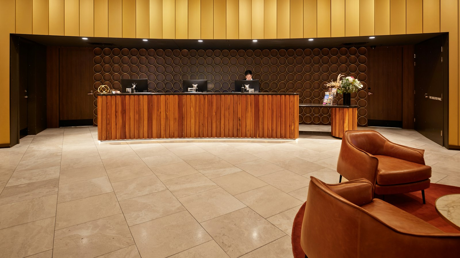 A hotel lobby with a wooden reception desk and armchairs (photo: Neon Wang / Unsplash)