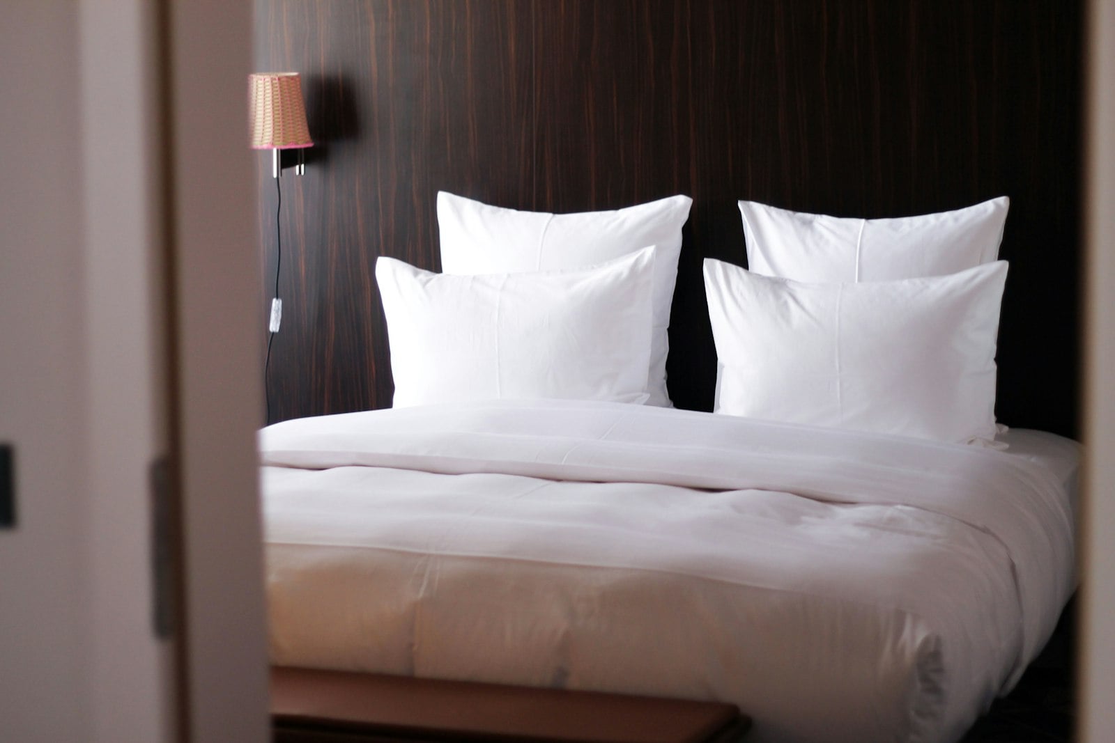 Hotel-style bed with stacked white pillows and crisp bedding (photo: Dave Photoz / Unsplash)