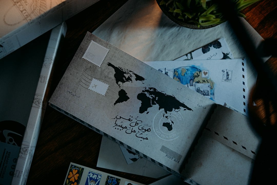 Stamped envelopes printed with a world map lie scattered on a dark wooden table