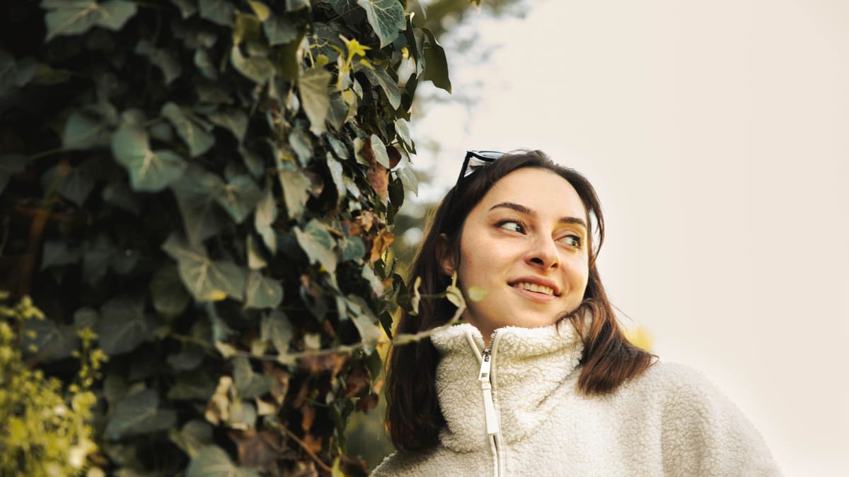 Woman in a fleece jacket standing outdoors beside ivy