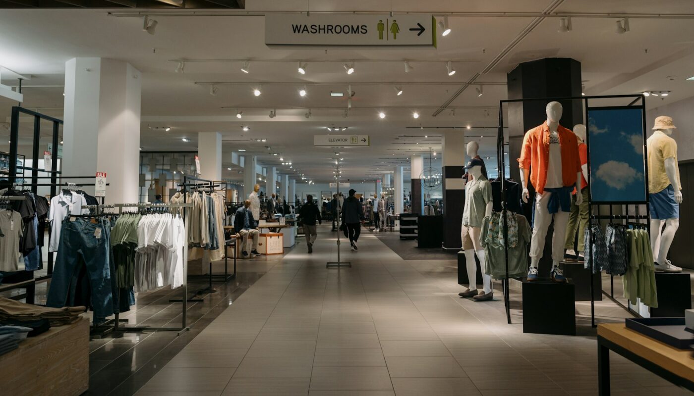 A bright department store floor with clothing rails and mannequins (photo: Albert Stoynov / Unsplash)