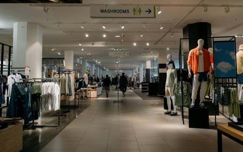 A bright department store floor with clothing rails and mannequins (photo: Albert Stoynov / Unsplash)
