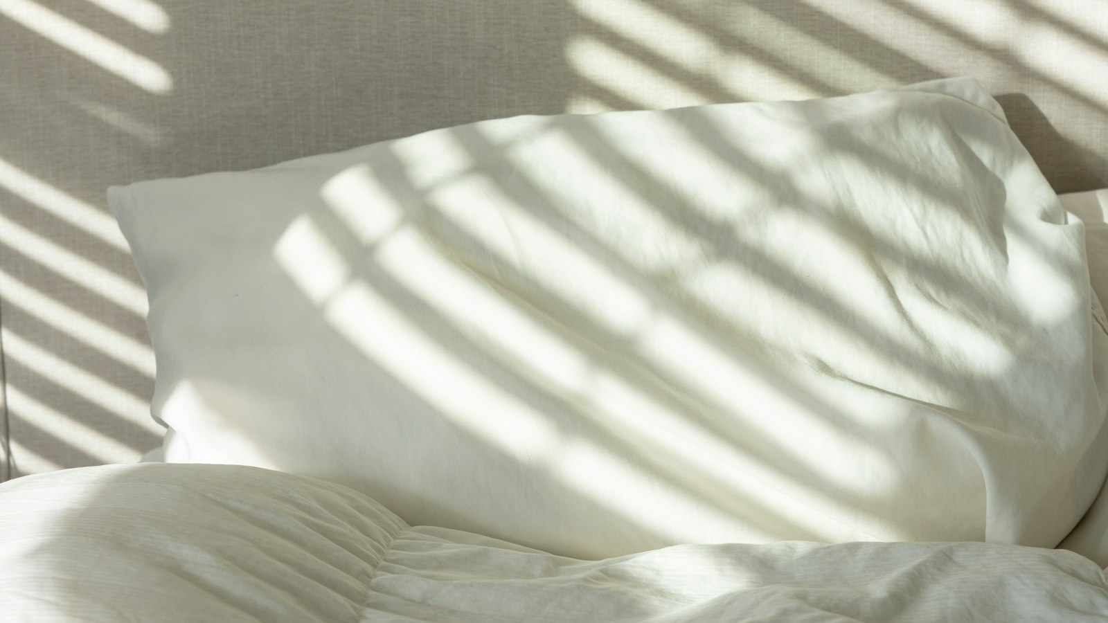 White bedding and pillows in soft window light (photo: Liz Vo / Unsplash)