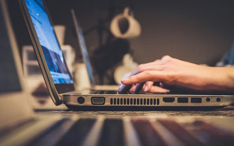 Hands typing on a laptop keyboard with the screen lit