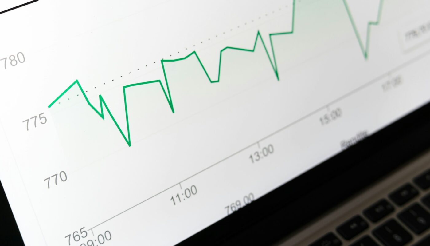 A close view of a green line chart rising and falling across a laptop screen (photo: Markus Winkler / Unsplash)