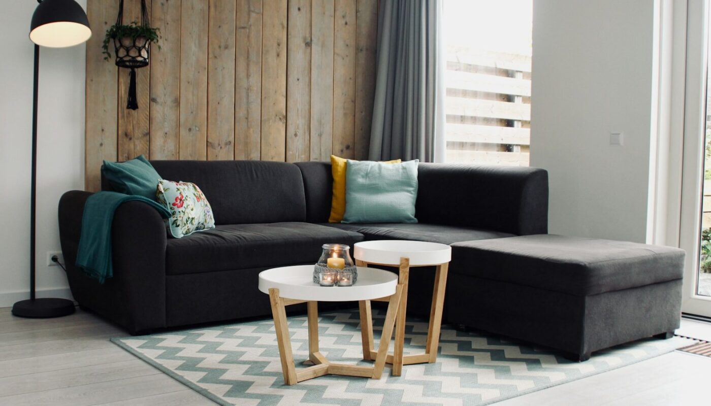 Lit candle on a round white coffee table beside a sectional sofa (photo: Sven Brandsma / Unsplash)