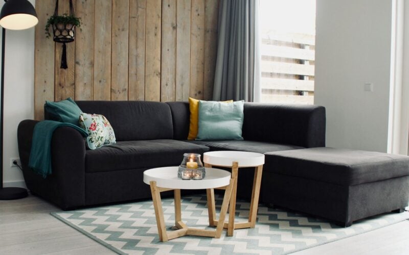 Lit candle on a round white coffee table beside a sectional sofa (photo: Sven Brandsma / Unsplash)
