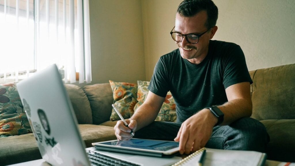 Man in a black t-shirt working on a MacBook Air at a desk (photo: Kit / Unsplash)