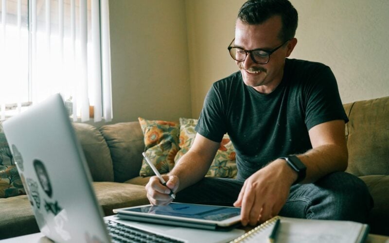 Man in a black t-shirt working on a MacBook Air at a desk (photo: Kit / Unsplash)