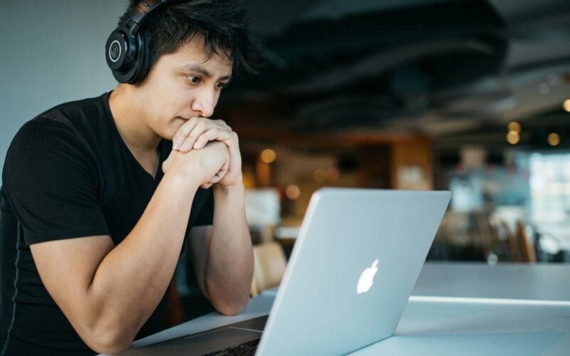 Man wearing headphones studying at a MacBook (photo: Wes Hicks / Unsplash)