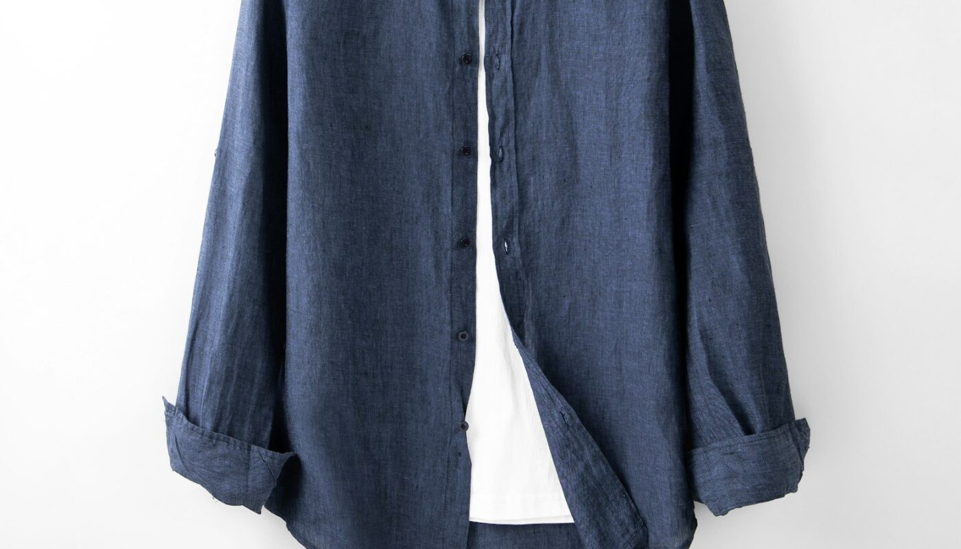 A blue linen shirt on a hanger against a white wall (photo: Robert Richman / Unsplash)