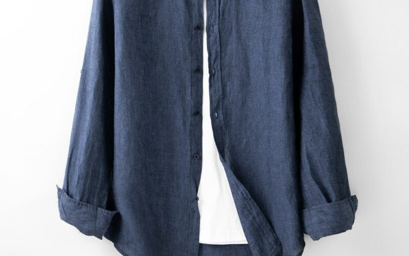 A blue linen shirt on a hanger against a white wall (photo: Robert Richman / Unsplash)
