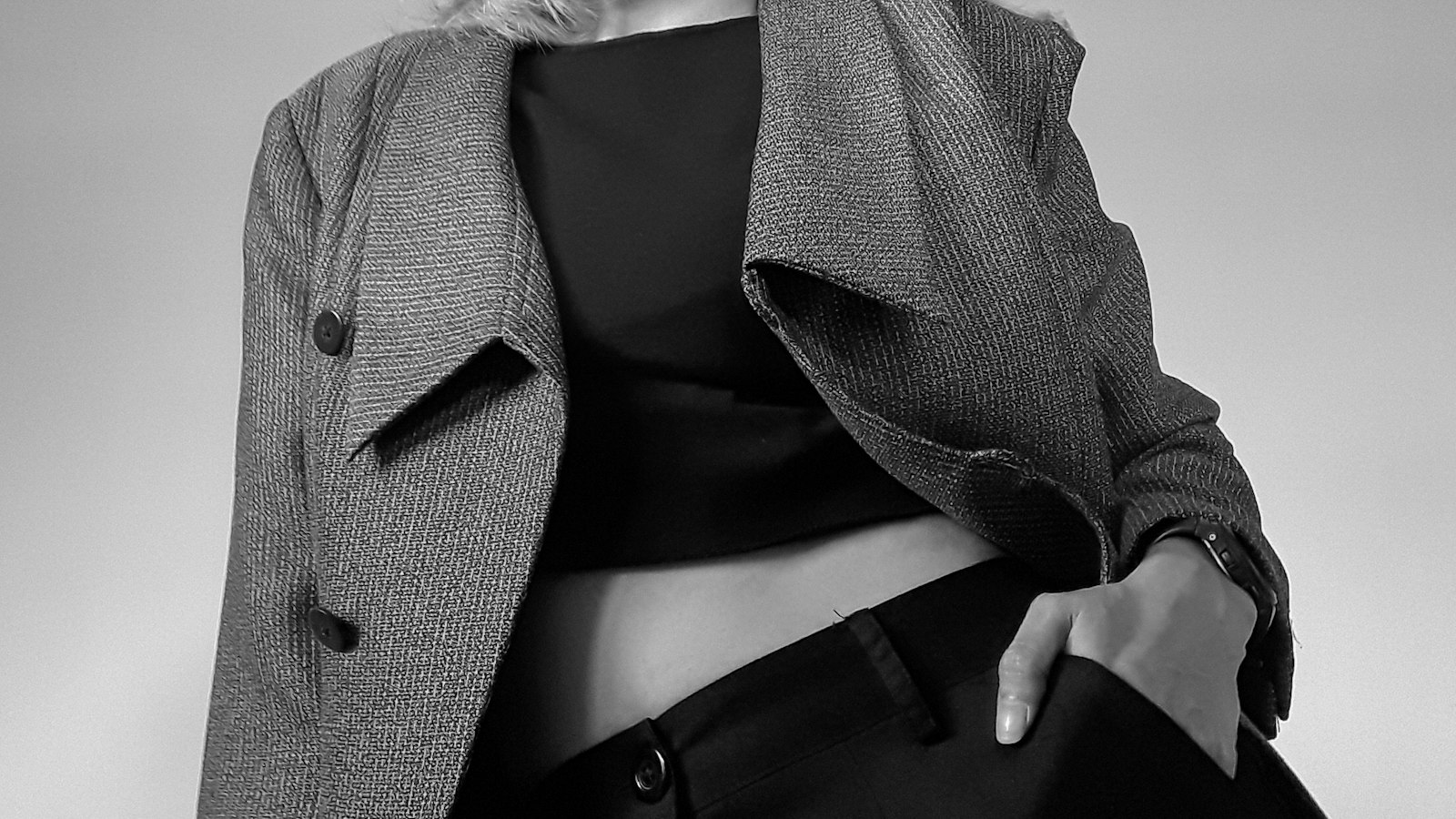 A woman in a grey tweed coat, photographed in black and white (photo: Chyntia Juls / Unsplash)