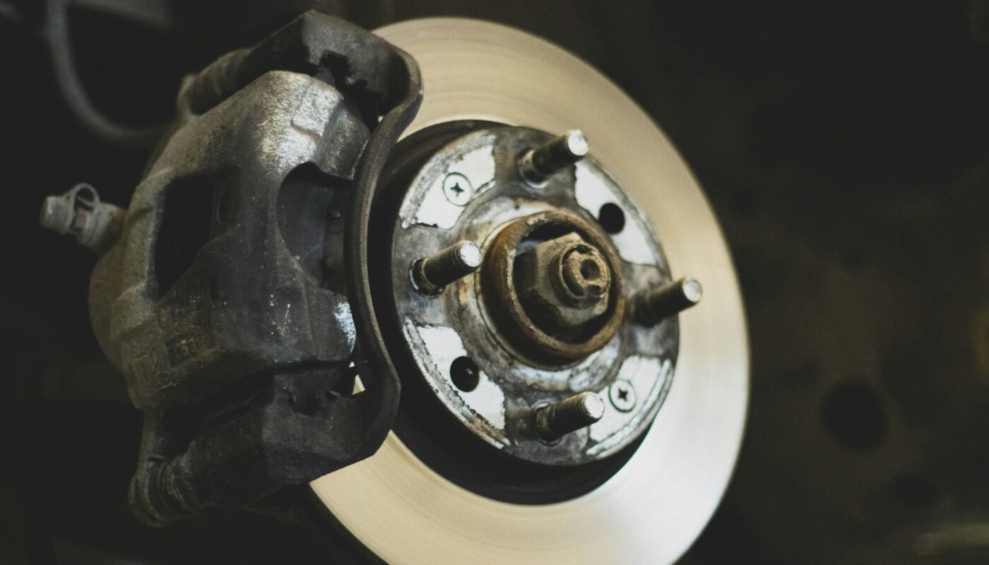 A car brake disc and caliper exposed with the wheel removed (photo: Benjamin Brunner / Unsplash)