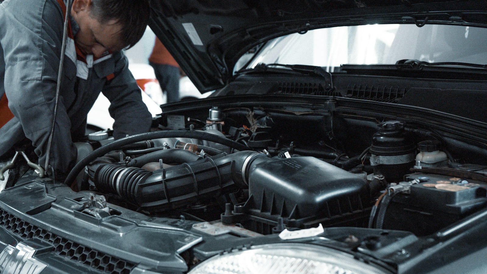 A mechanic working in an open engine bay (photo: Kate Ibragimova / Unsplash)
