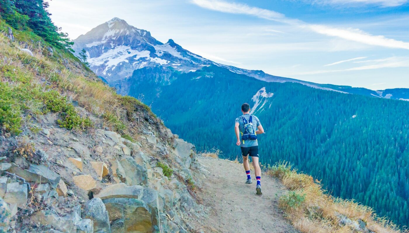 A runner on a mountain trail with a snow-capped peak behind (photo: Brian Erickson / Unsplash)