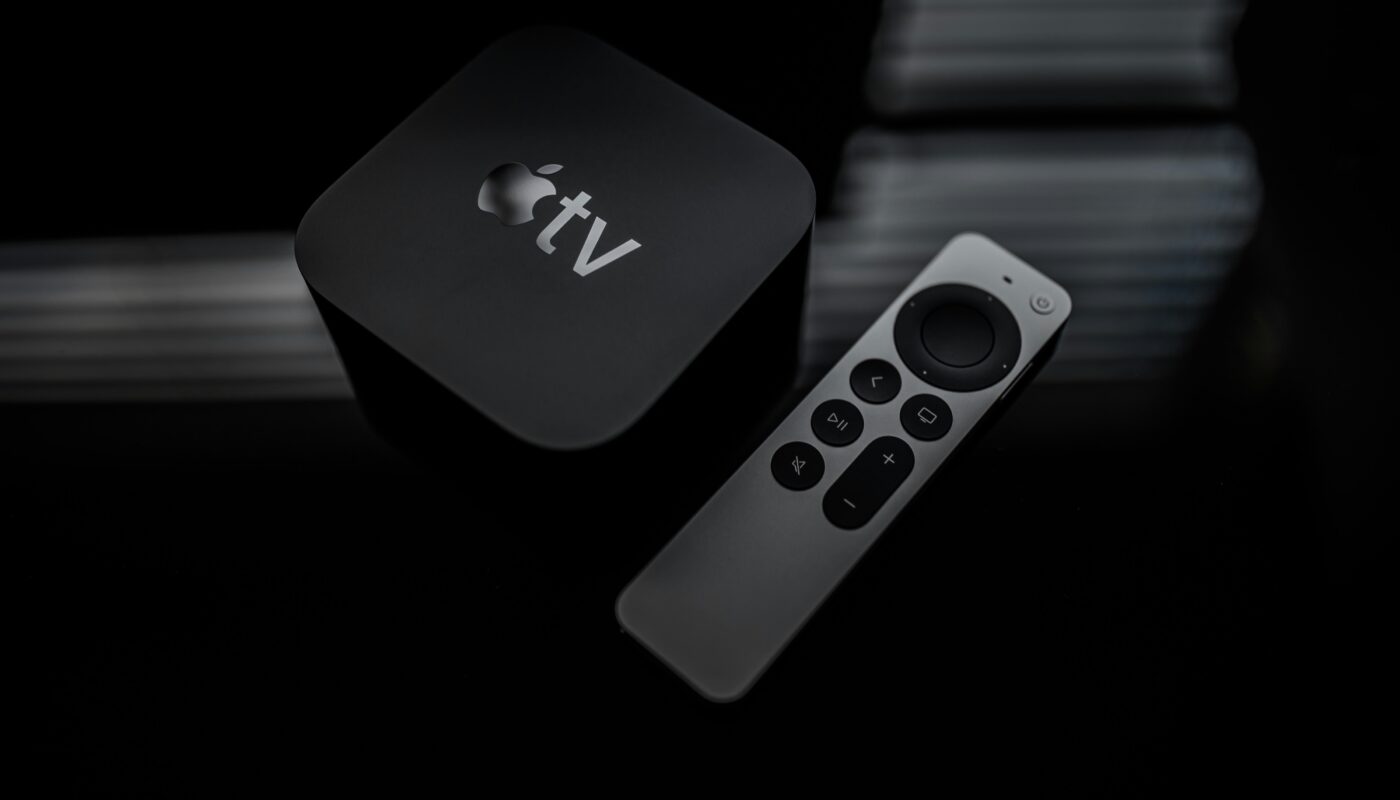 Apple TV streaming box beside its remote control