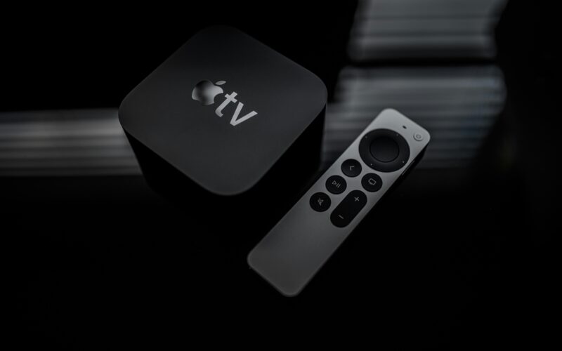 Apple TV streaming box beside its remote control