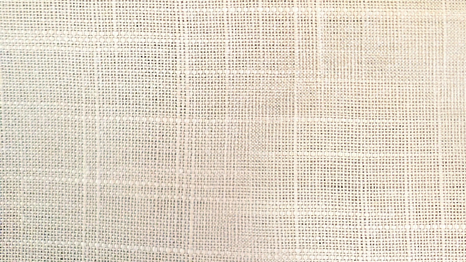 A macro view of pale open-weave linen showing the gaps between warp and weft threads